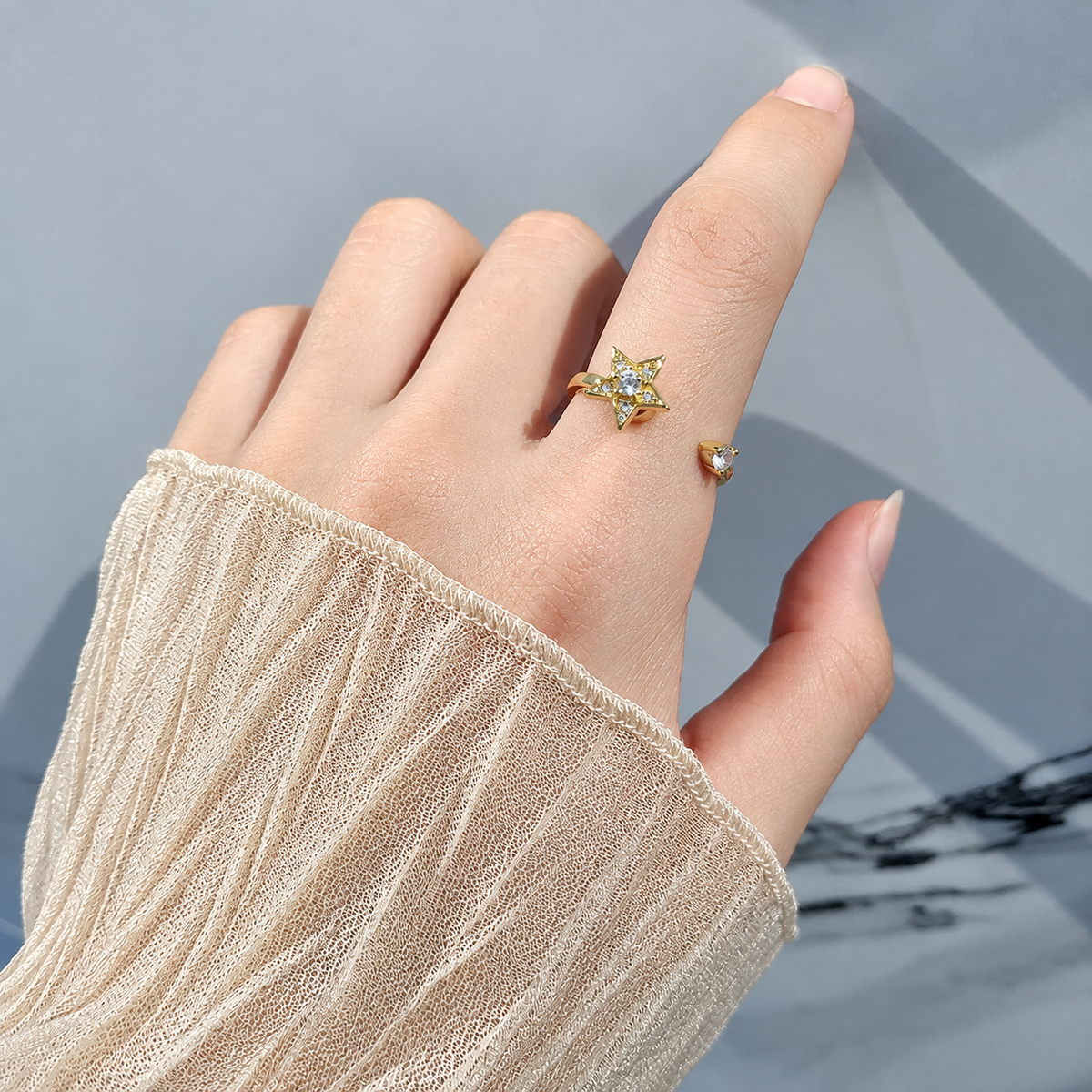 Bague anti-stress rotative Étoile dorée, étoile pavée de petites pierres et pierre centrale, portée au doigt