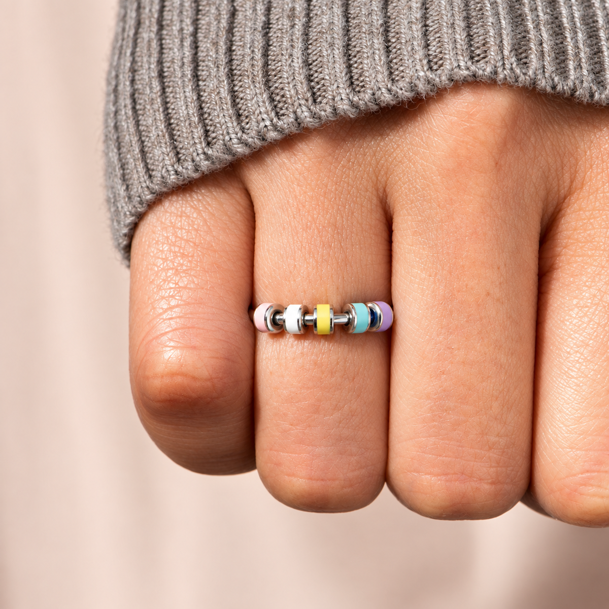 Bague anti-stress bille Colorée, jonc ouvert à rondelles émaillées pastel, portée au doigt