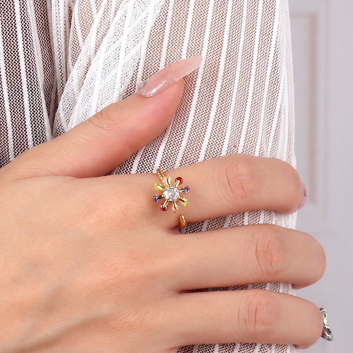 Bague anti-stress rotative Amas dorée, étoile de pierres multicolores autour d’une pierre claire, anneau torsadé, portée au doigt