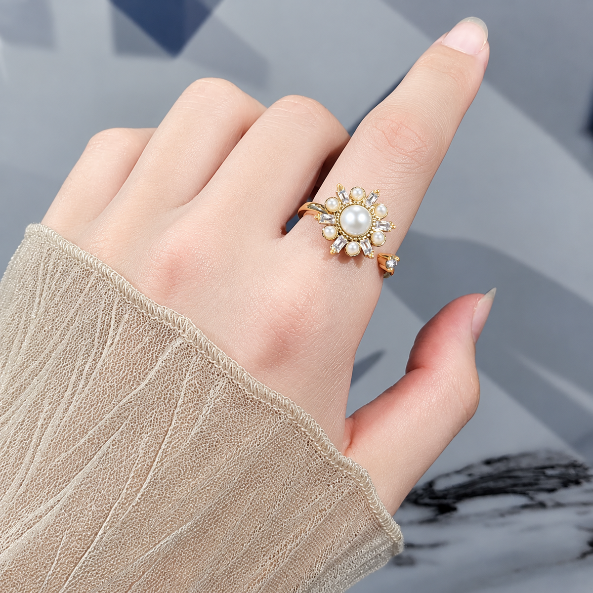 Bague anti-stress rotative Astre dorée, astre de perles blanches aux rayons de pierres taille baguette, portée au doigt