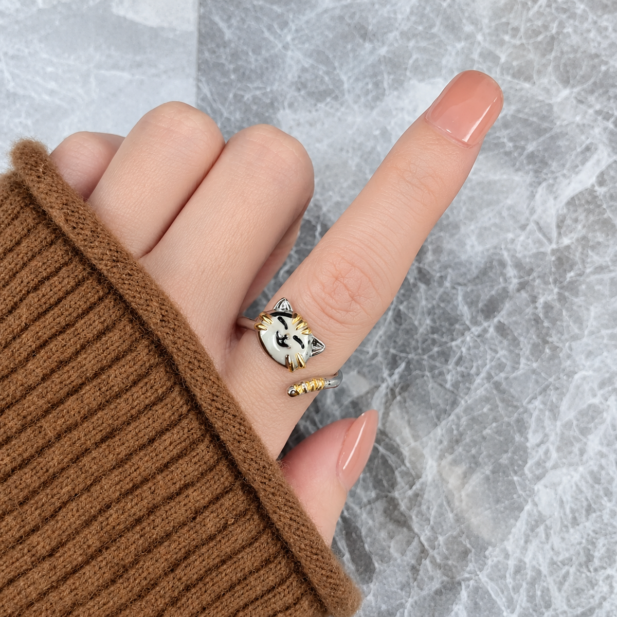 Bague anti-stress rotative Chat Mignon, tête de chat argentée aux détails dorés, queue enroulée, portée au doigt
