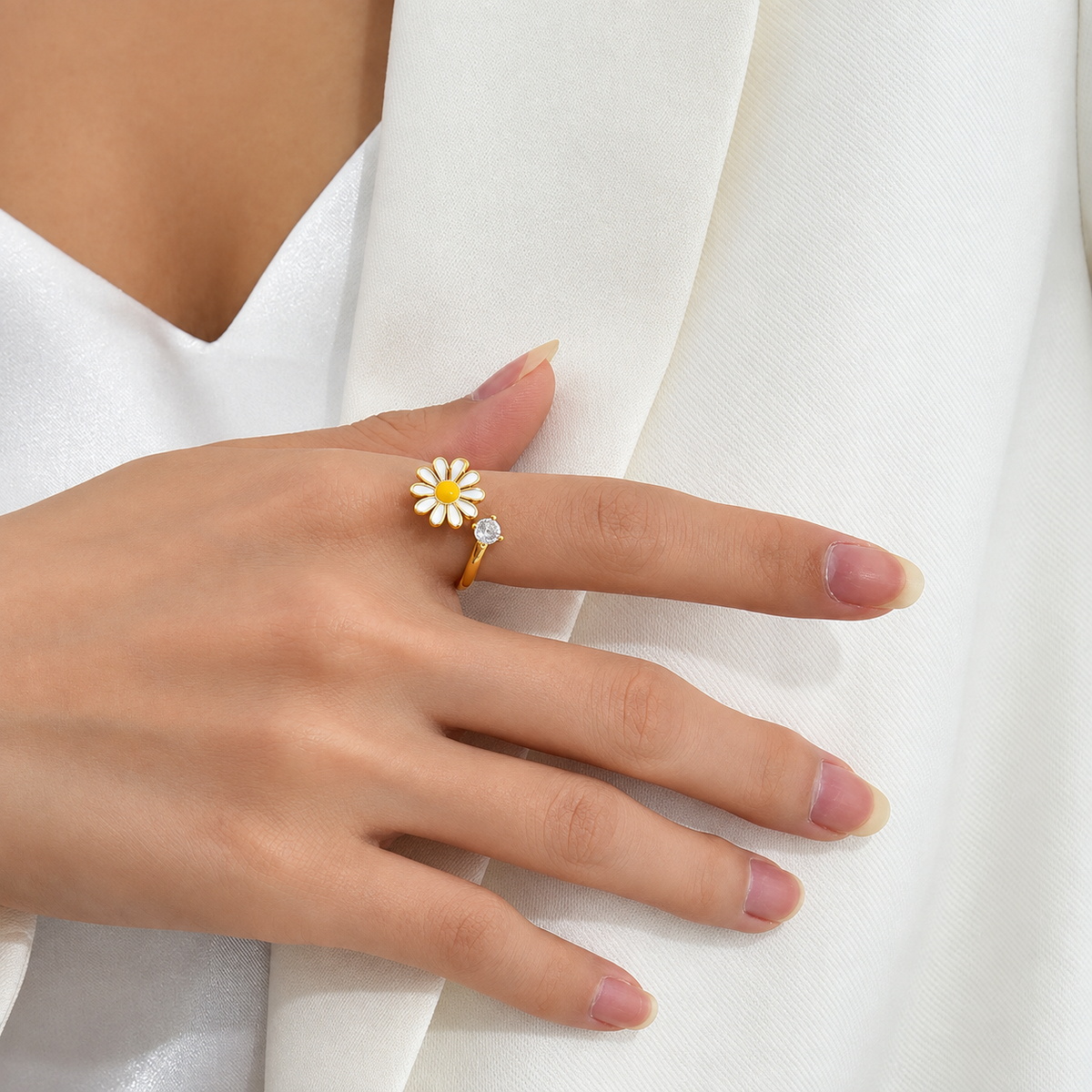 Bague anti-stress rotative Daisy, pâquerette émaillée blanche au cœur jaune, pierre sertie, portée au doigt