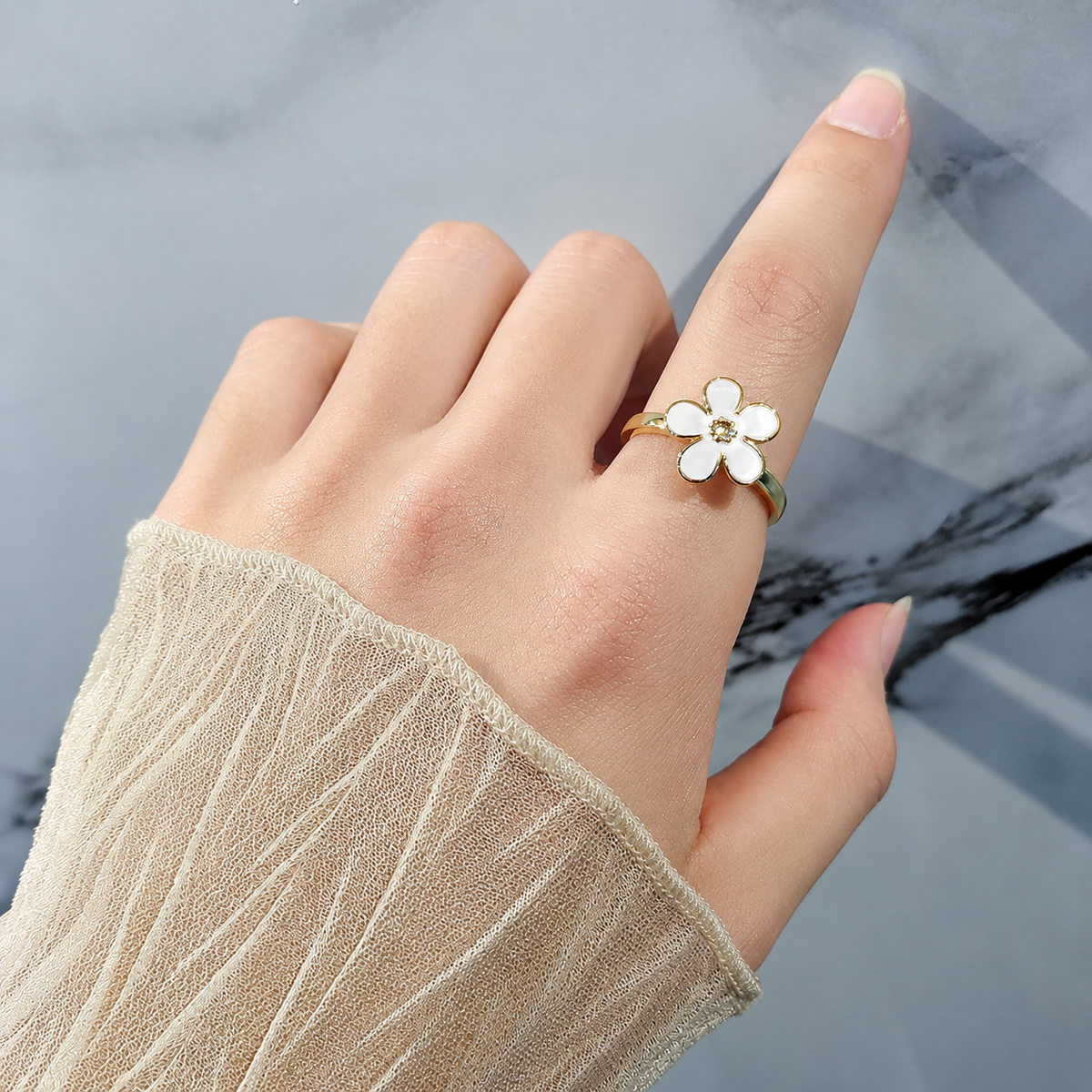 Bague anti-stress rotative Fleur Design, fleur émaillée à cinq pétales et cœur doré perlé, portée au doigt