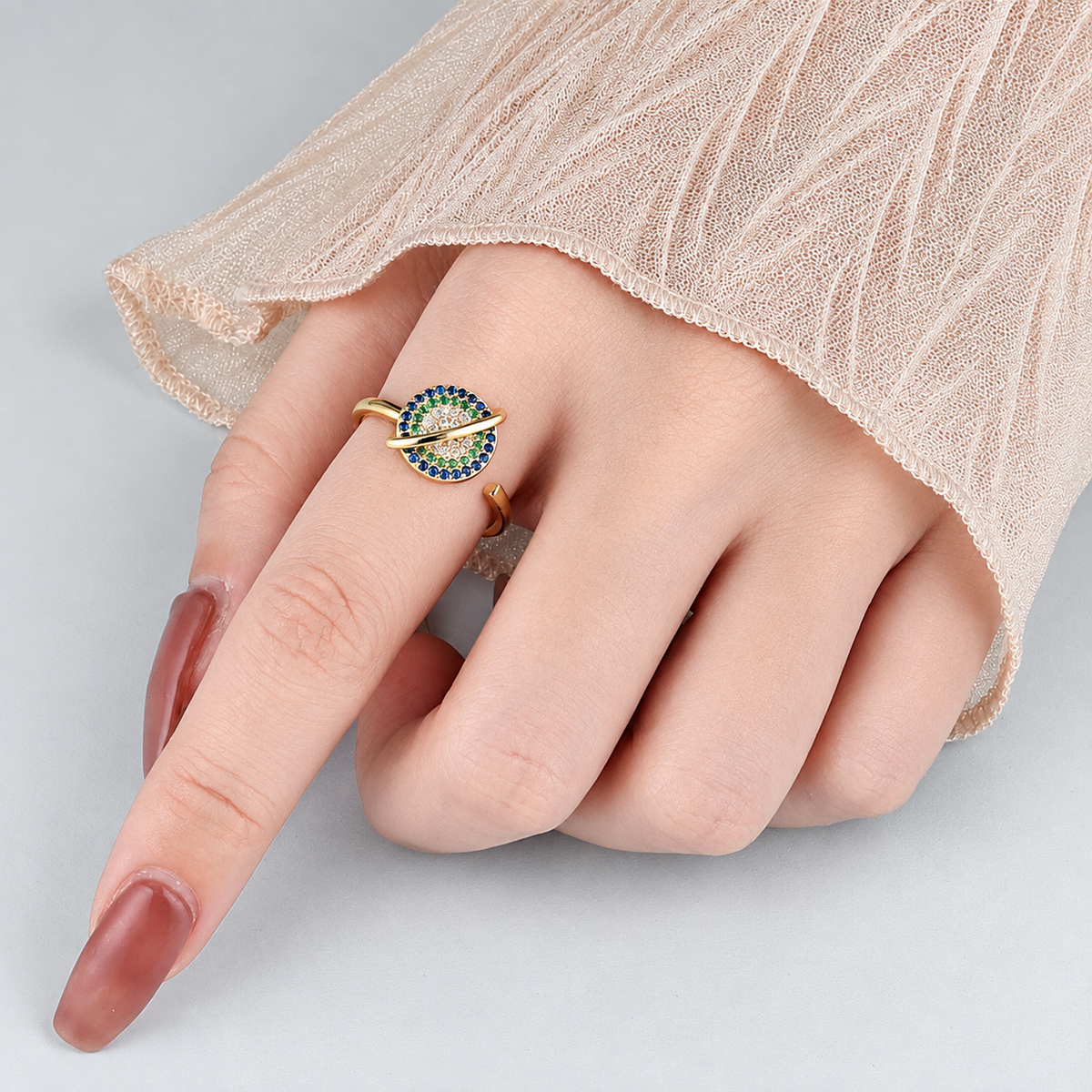 Bague anti-stress rotative Galaxie dorée, galaxie ceinte d’un anneau, sertie de pierres bleues, vertes, blanches et orangées, portée au doigt