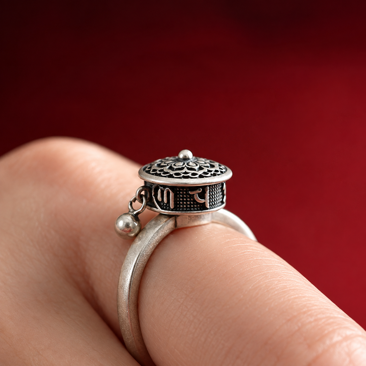 Bague anti-stress rotative Lotus Sacré, cylindre en argent vieilli ciselé d’un lotus, pampille perlée, portée au doigt