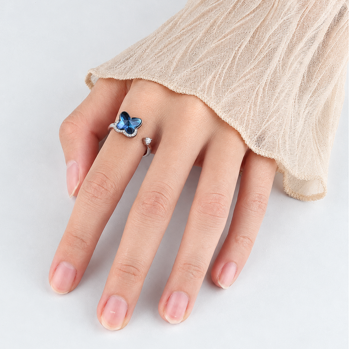 Bague anti-stress rotative Papillon Galactique, papillon en cristal bleu facetté bordé de petites pierres, portée au doigt