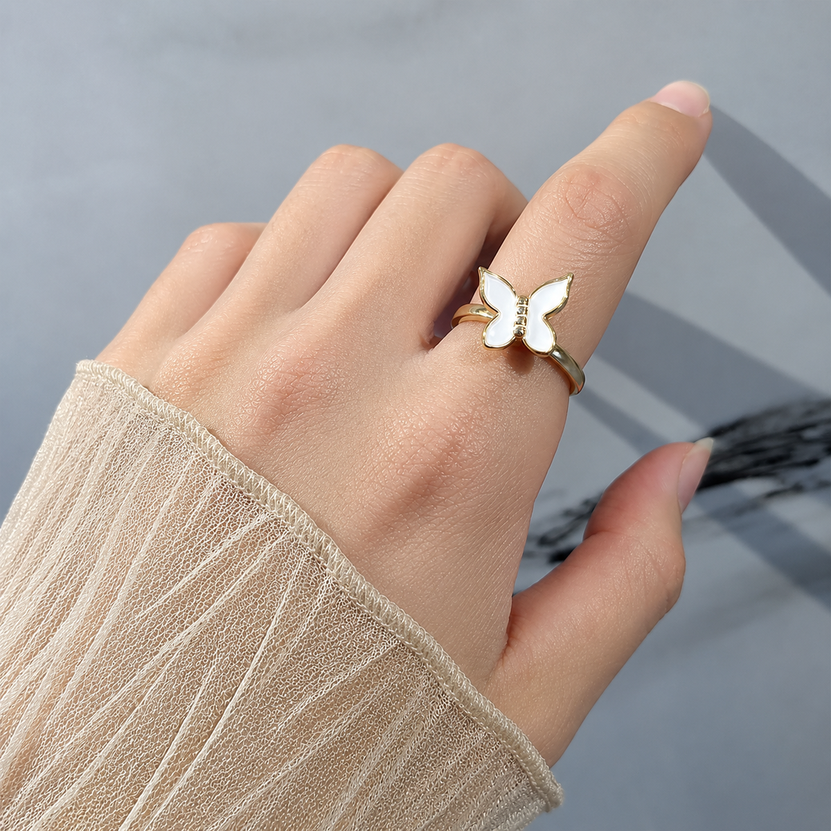 Bague anti-stress rotative Papillon, papillon à une aile émaillée blanche et une aile ajourée, portée au doigt
