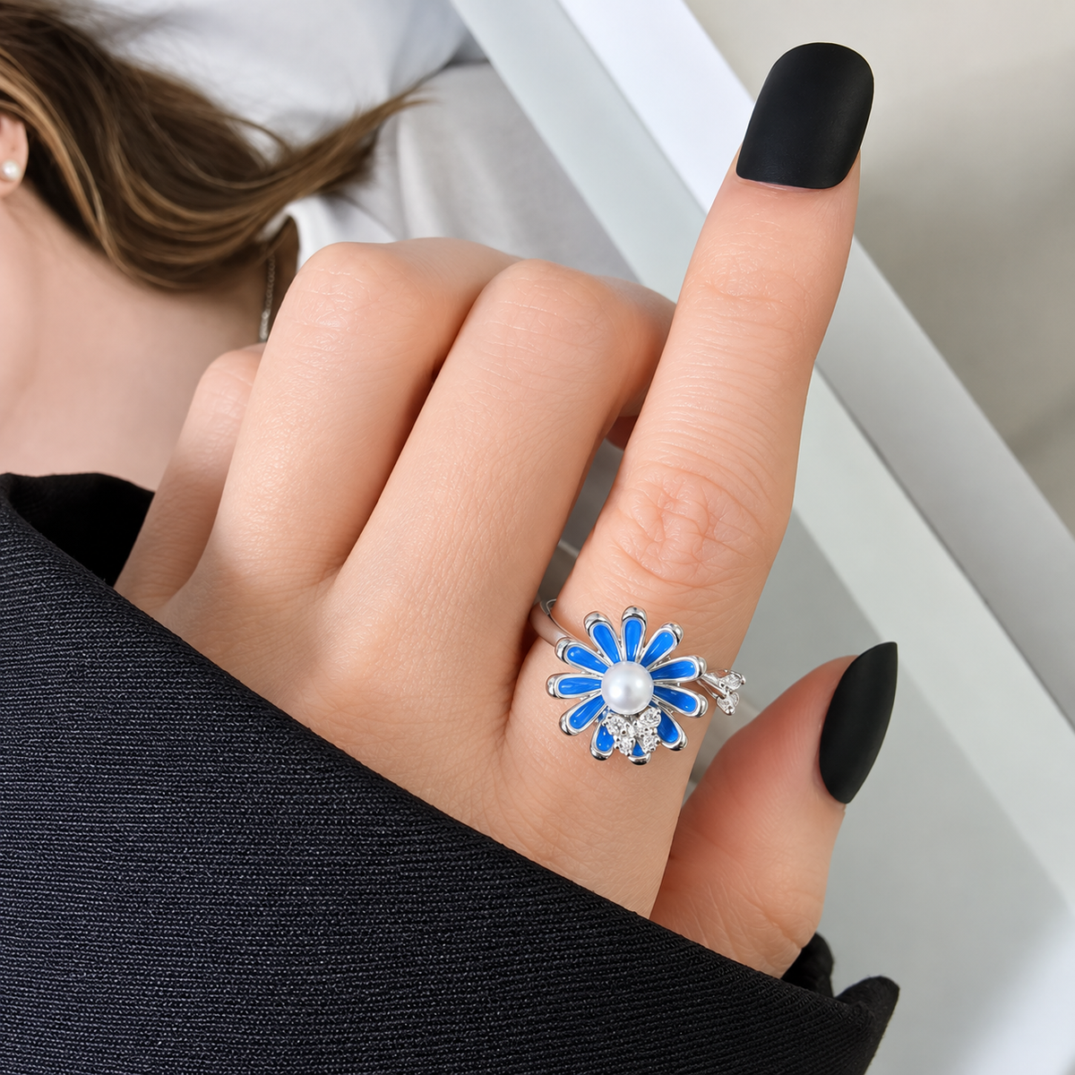 Bague anti-stress rotative Papillon Printanier, papillon pavé posé sur une fleur émaillée bleue au cœur de perle, portée au doigt