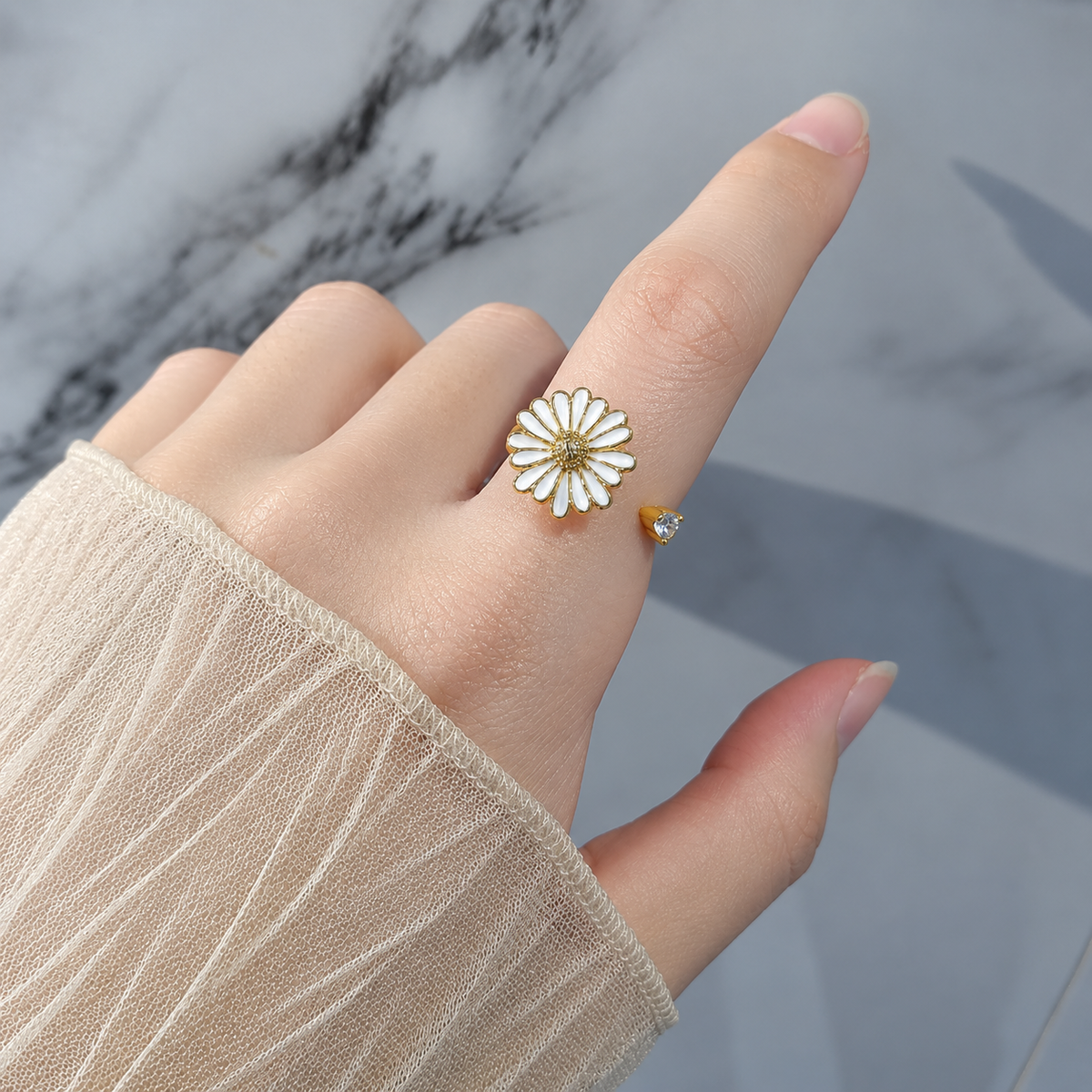 Bague anti-stress rotative Pâquerette dorée, pâquerette émaillée blanche au cœur doré texturé, portée au doigt