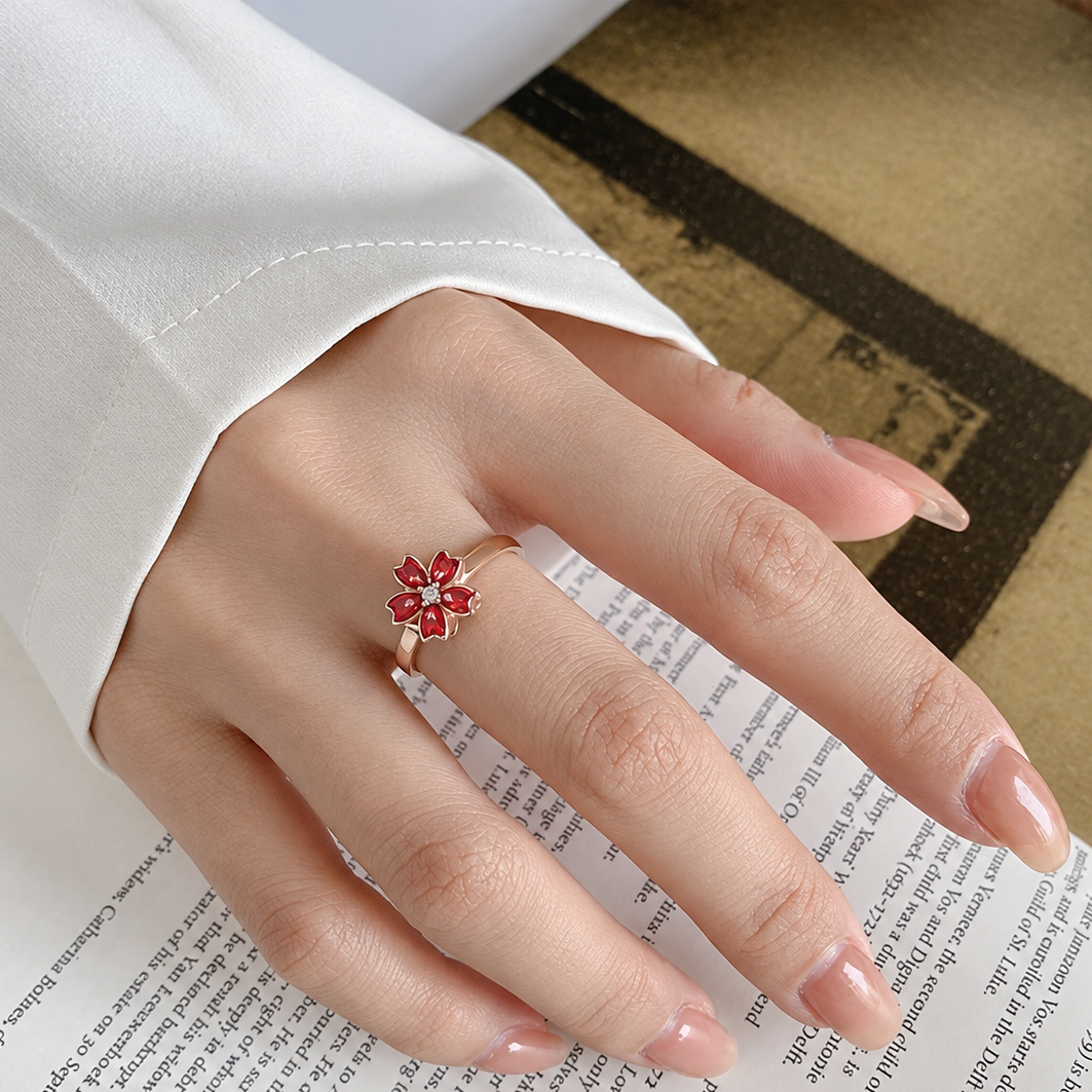 Bague anti-stress rotative Pétale Ardente, fleur de cerisier en émail rouge sur anneau rosé, portée au doigt