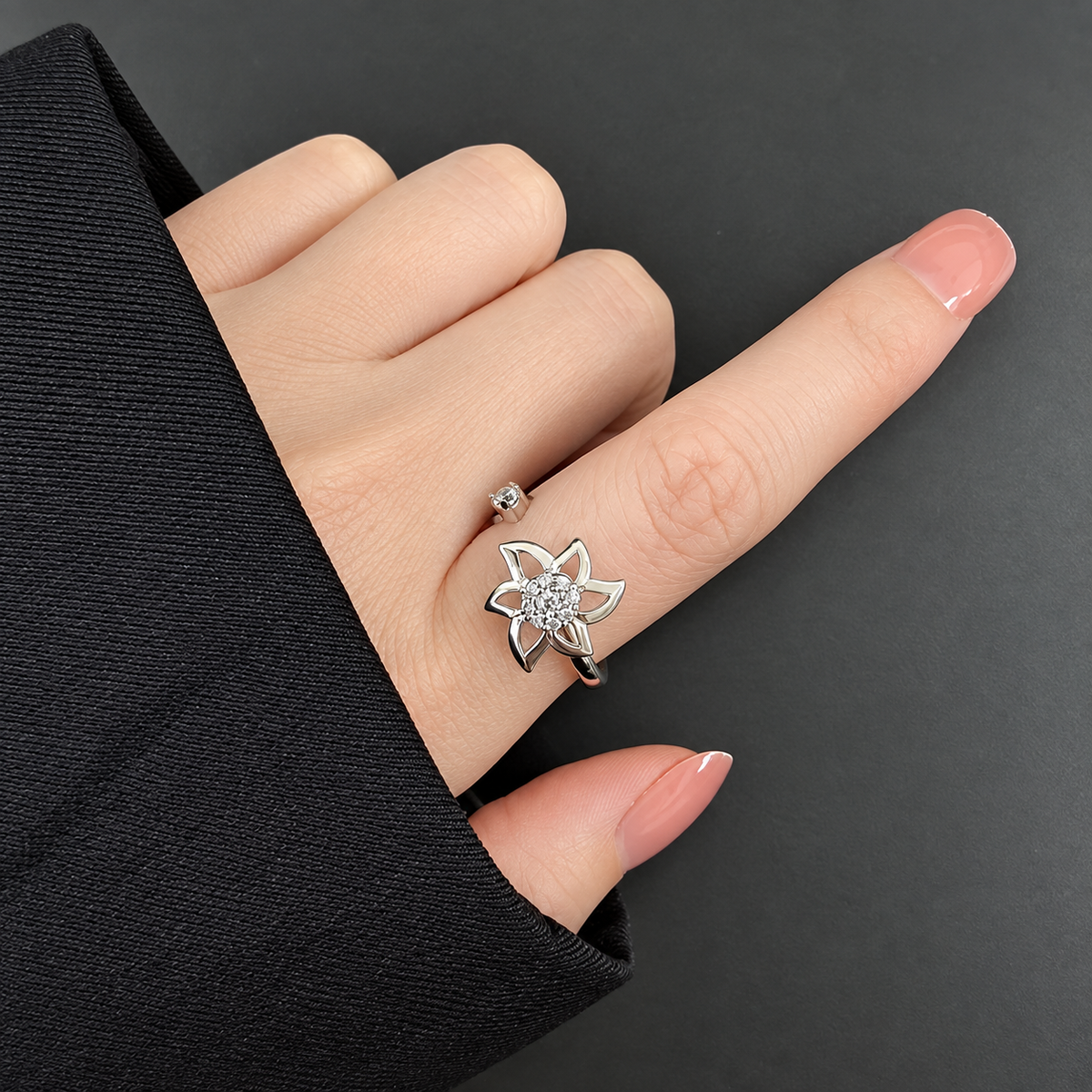 Bague anti-stress rotative Pétale Tranchante, fleur ajourée aux pétales effilés, cœur pavé, portée au doigt