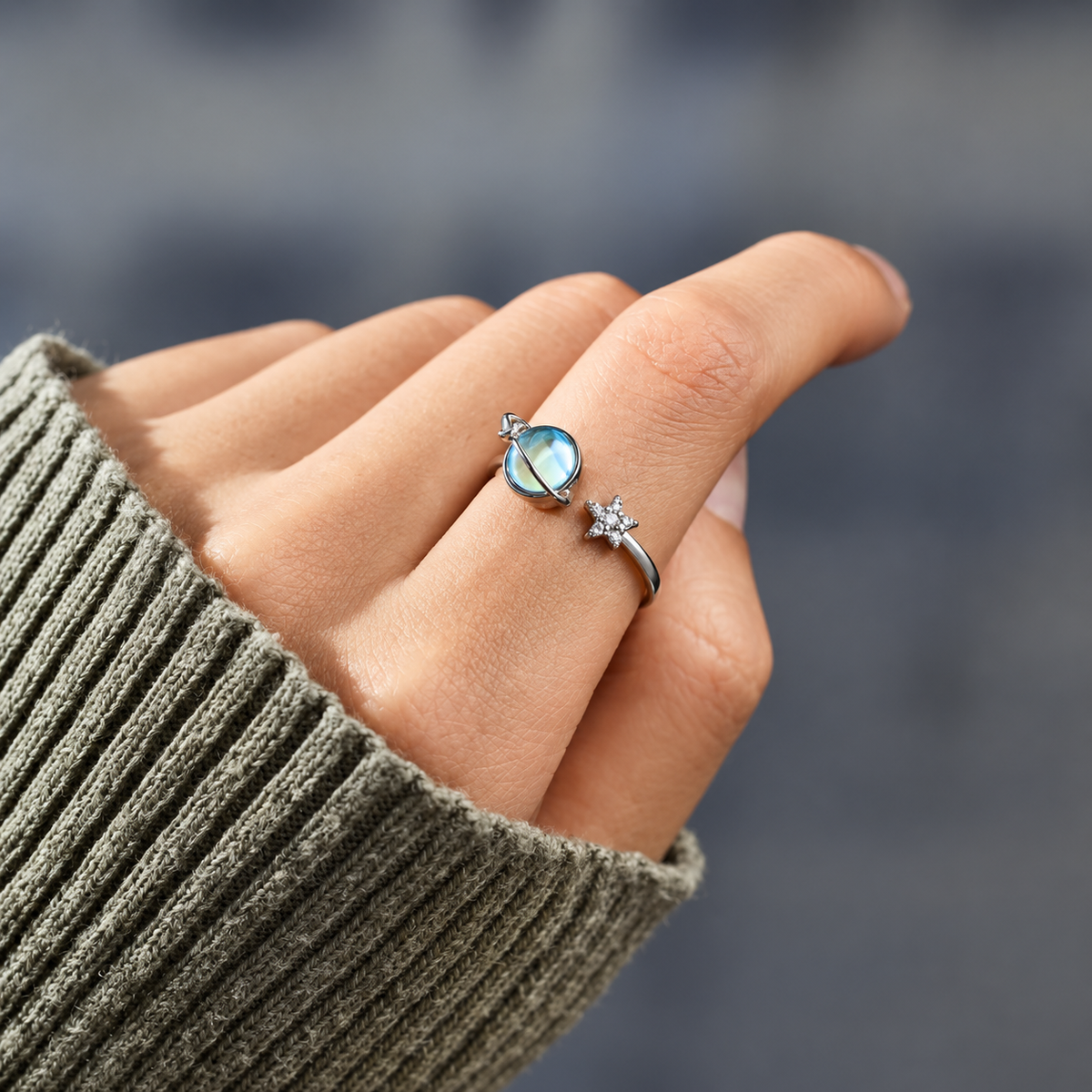 Bague anti-stress rotative Reflet Lunaire, lune en pierre aux reflets bleutés cerclée d’un anneau, étoile pavée, portée au doigt